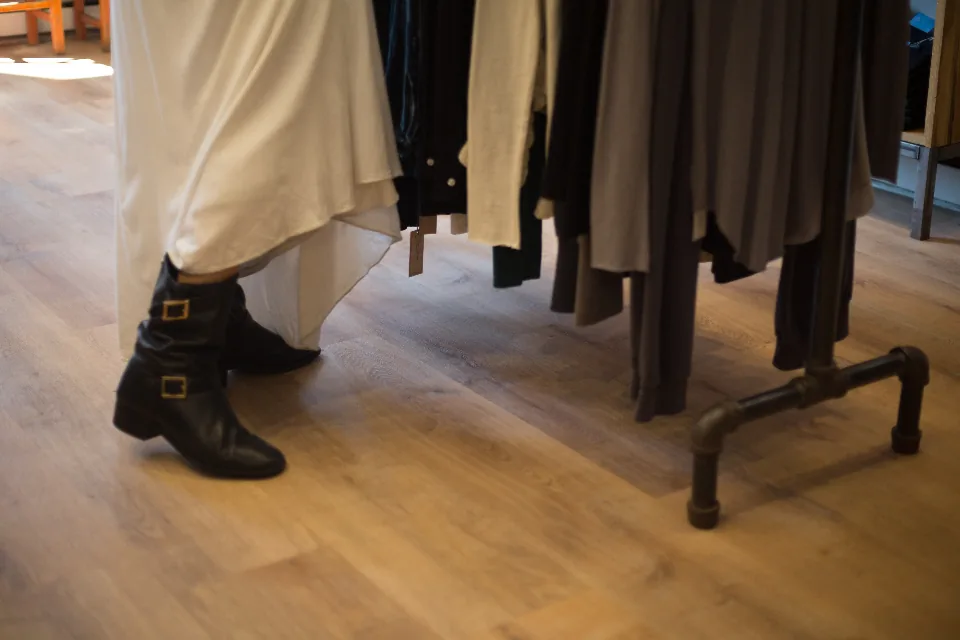 Customer in black boots browsing a clothing rail inside a store